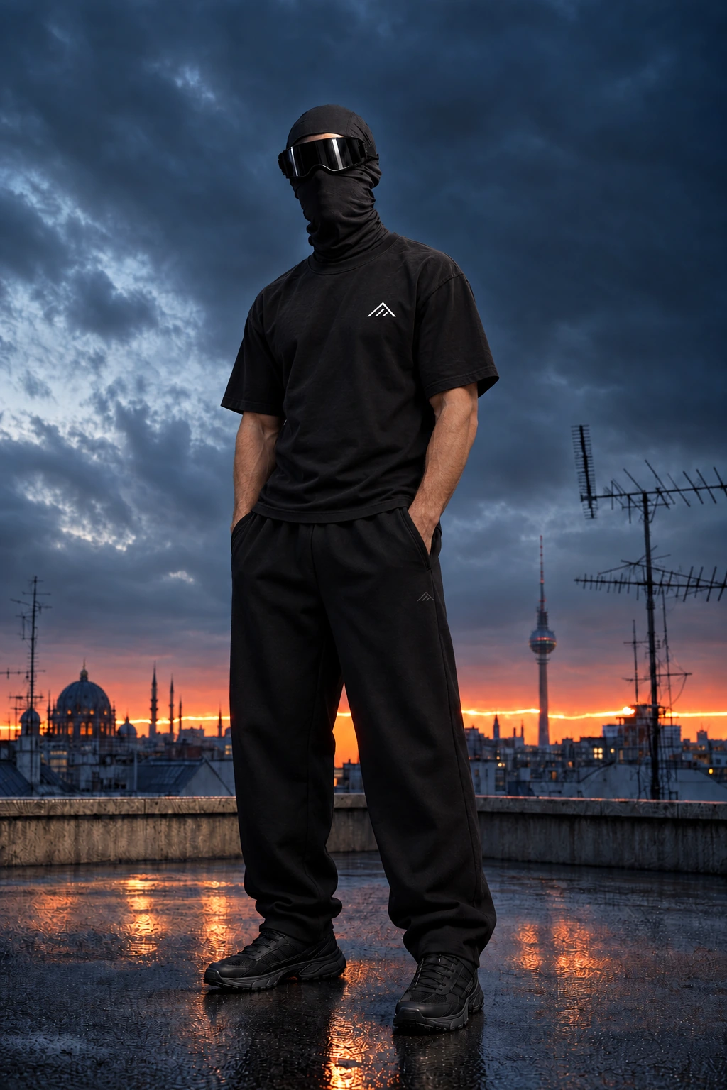 Masked model in the black relaxed gym tee and wide-leg sweatpants on a city rooftop